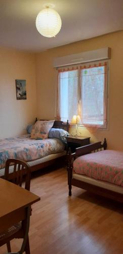 een slaapkamer met 2 bedden, een tafel en een raam bij ferme équestre des abrons in Pailloles