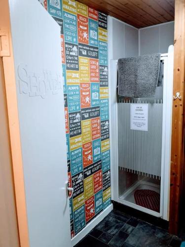 a bathroom with a shower with a wall covered in signs at aabAlree Guest House in Dundee