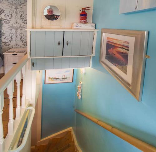 una scala con una parete blu con un mobile bianco di Birds Nest Cottage Looe a Looe