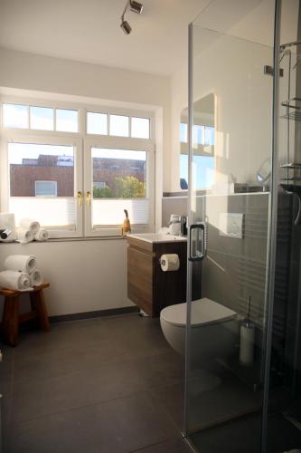 a bathroom with a shower and a toilet and a sink at Residenz Strandläufer in Wenningstedt