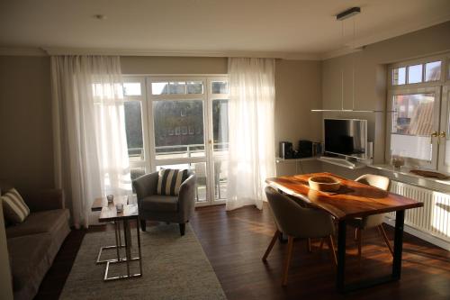 a living room with a table and chairs and a kitchen at Residenz Strandläufer in Wenningstedt