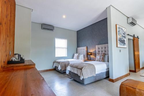 two beds in a bedroom with white walls and wood floors at Beach Wood Boutique Hotel & Resort in Ballito