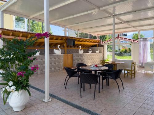 een patio met een tafel, stoelen en bloemen bij Villa Romantika in Chrysi Ammoudia