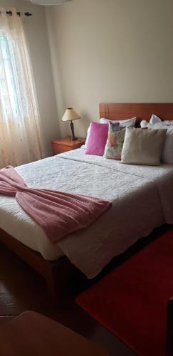 a bedroom with a large bed with purple and white pillows at Casa da Ribeira in Povoação