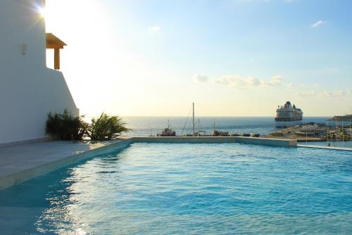 a swimming pool with a cruise ship in the ocean at Calistus Mykonos in Mikonos