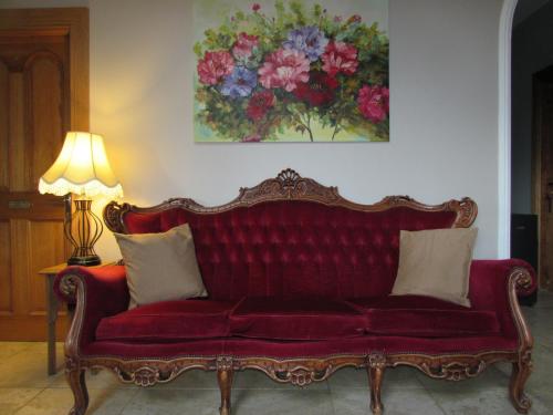 a red couch in a living room with a painting on the wall at Dungimmon House in Ballyconnell