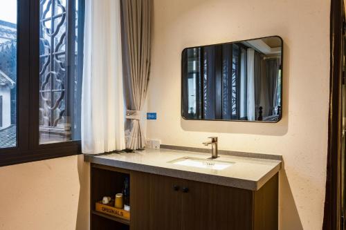 een badkamer met een wastafel en een spiegel bij Tongli 1917 Best South Inn in Suzhou