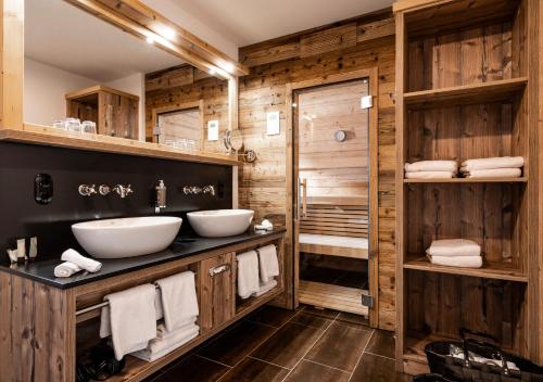 巴特欣德朗Alpin Lodges - Moderne Appartements mit Zugang zu 3000 qm SPA Panoramahotel Oberjoch的一间带两个水槽和木墙的浴室