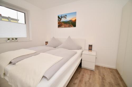 a white bedroom with a large bed and a window at WINETIME - modern - für 5 - idyllisch - Netflix in Roschbach