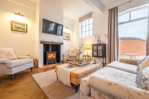 a living room with a couch and a fireplace at Crisply stylish Georgian cottage - Orchard Coach House in Sudbury
