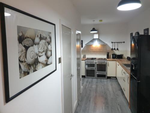 a kitchen with white cabinets and a black refrigerator at Stunning 5 bed house, 2 mins to beach and town, with free parking in Blackpool