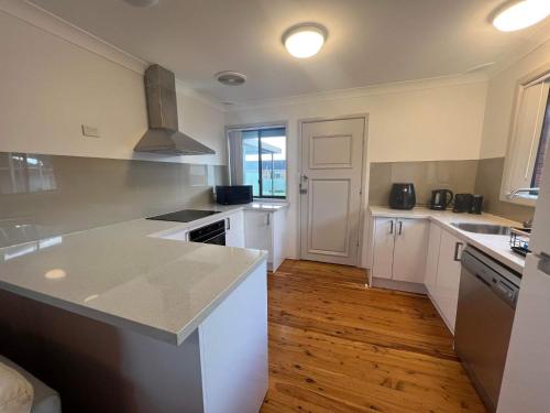 a kitchen with white appliances and a wooden floor at The Entrance & Shelly Beach Holiday House in Long Jetty