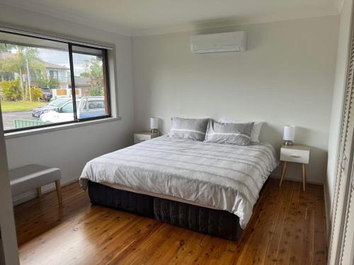 a bedroom with a large bed and a window at The Entrance & Shelly Beach Holiday House in Long Jetty