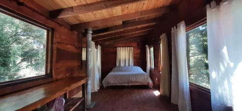 1 dormitorio en una cabaña de madera con 2 ventanas en Titania Traful en Villa Traful