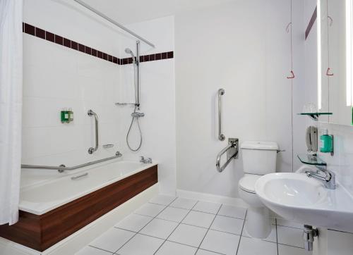 a bathroom with a tub and a toilet and a sink at Leonardo Hotel Milton Keynes in Milton Keynes