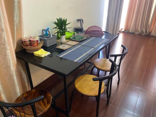 uma mesa preta com três cadeiras e uma mesa com comida em Gvai Apartment em Phnom Penh