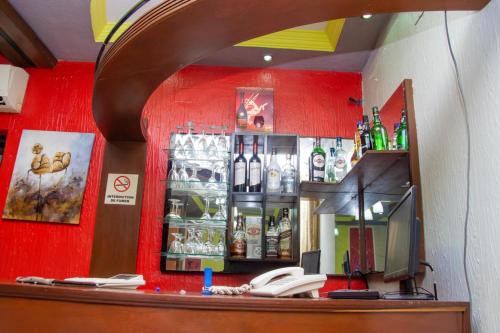 een bar met een rode wand met flessen alcohol bij Appartement de 3 chambres avec balcon et wifi a KinshasaELv in Kinshasa