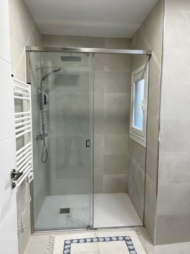 La salle de bains est pourvue d'une douche avec une porte en verre. dans l'établissement PISO CENTRO - CONCORDIA, à Ourense