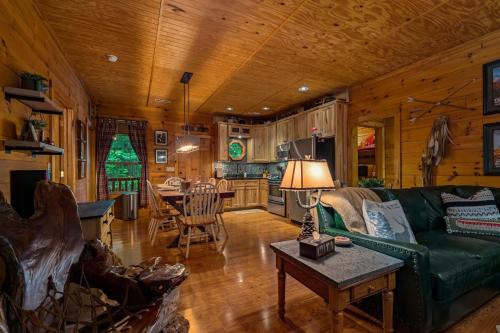 a living room with a green couch and a kitchen at Dreamy Cabin & Outdoor Oasis! Mins to Nat'l Park! in Townsend