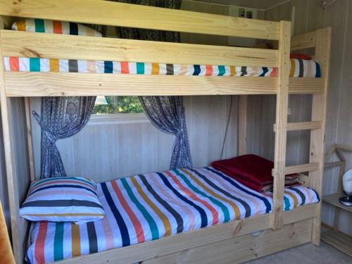 a wooden bunk bed with a colorful striped sheets at Gîte pèlerin - "Les Sources" - Chambres Dortoirs in Le Vigan