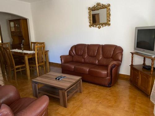 sala de estar con sofá de cuero marrón y mesa en Casa dos Avós, en Alvares