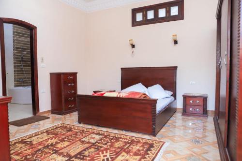 a bedroom with a bed with a wooden headboard and a rug at Tomorrow Land villa in Luxor