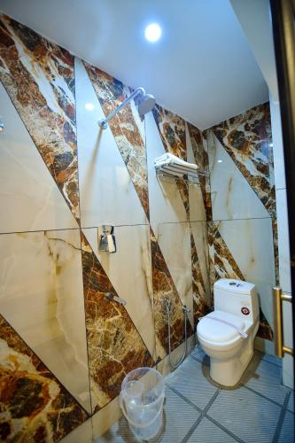a bathroom with a toilet and a tile wall at Hotel Surya Lodge in Mysore