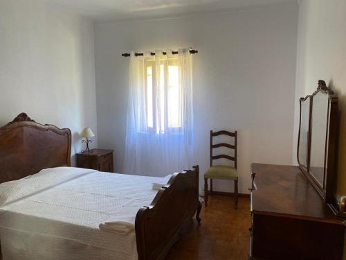 a bedroom with a bed and a desk and a window at Casa dos Avós in Alvares