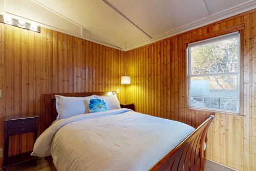 a bedroom with a bed with wooden walls and a window at Ozark Rambler Cabin in Eureka Springs
