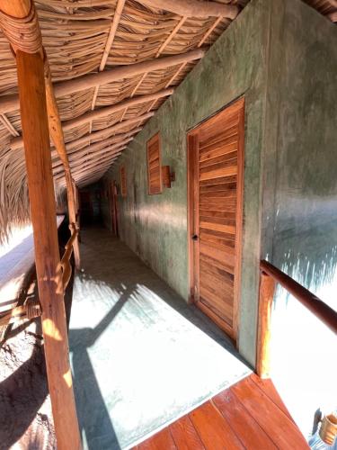 un couloir vide d'une maison avec une porte en bois dans l'établissement COCOS HOTEL, à Zipolite