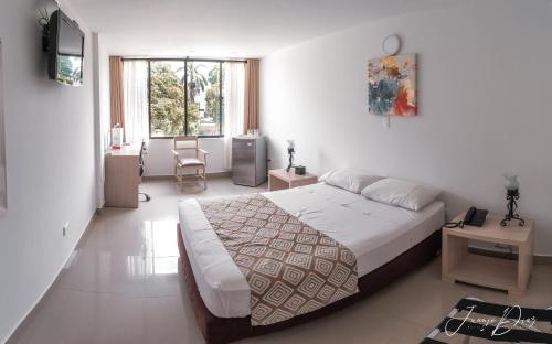 1 dormitorio con cama, escritorio y ventana en Hotel Juan Maria, en Tuluá