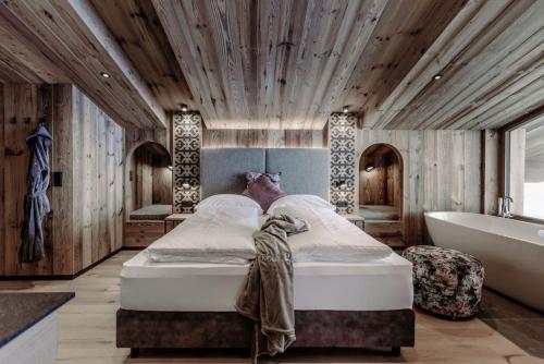 a bedroom with a bed and a tub and a sink at Biohof Ebengut in Maria Alm am Steinernen Meer