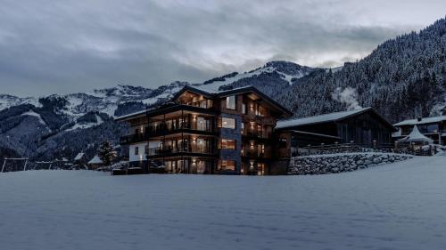 un grand bâtiment dans la neige devant les montagnes dans l'établissement Biohof Ebengut, à Maria Alm