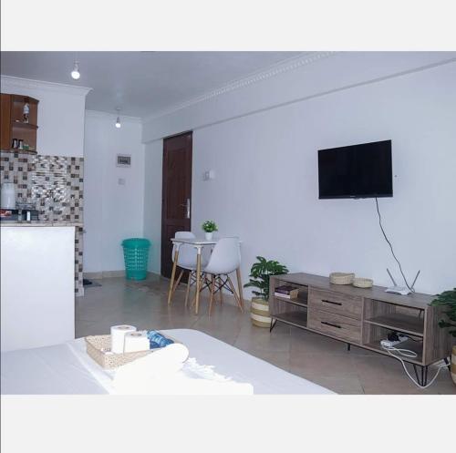 a living room with a tv and a table with chairs at Lux Suites Carina Studio Apartments in Bamburi