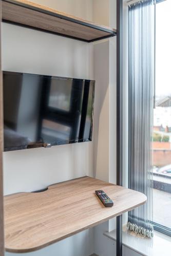 a tv on a wall next to a table with a remote control at Stylish Studio Apartment with Free Parking in Wolverhampton 5min walk to City Centre in Wolverhampton