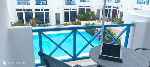 een laptop op een tafel op een balkon met een zwembad bij RED in Puerto del Carmen
