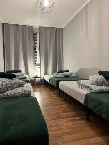 szereg łóżek w pokoju z drewnianą podłogą w obiekcie Apartament Nowowierzbowa 16 Zawiercie w mieście Zawiercie