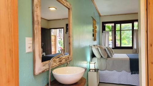 a bathroom with a sink and a bed and a mirror at Pousada da Ferrugem - Praia da Ferrugem in Garopaba