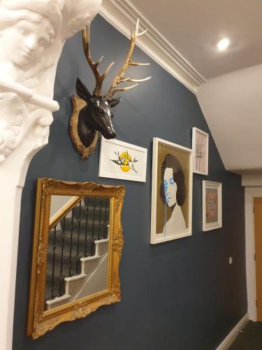 a hallway with a mirror and portraits on a wall at The Metropolitan Guest House in Whitley Bay