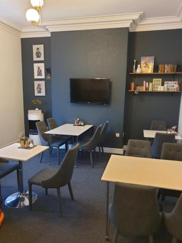 a waiting room with tables and chairs and a flat screen tv at The Metropolitan Guest House in Whitley Bay
