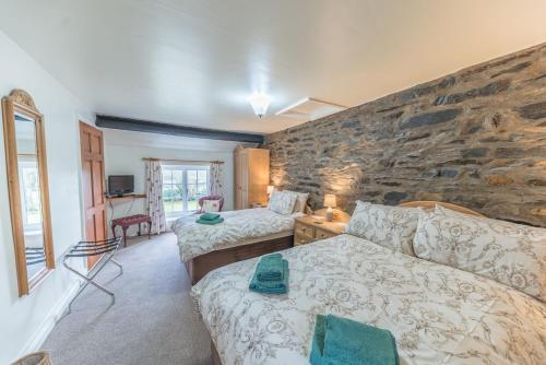 a bedroom with two beds and a stone wall at Middlefield Cottage Coniston Water in Coniston
