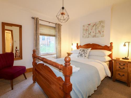 a bedroom with a bed and a chair and a window at Poppy Cottage in Ashbourne