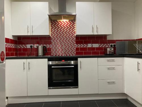 a kitchen with white cabinets and a black oven at Winter Gardens North Pier Home in Blackpool