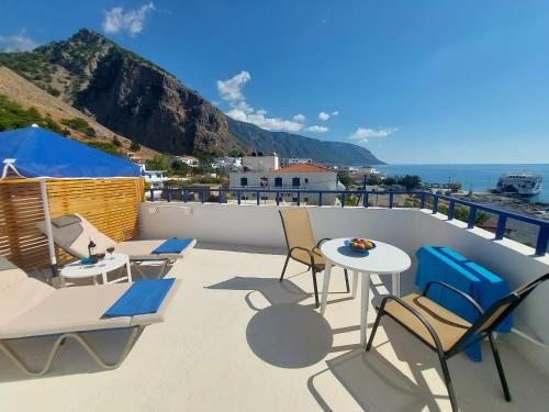 a balcony with chairs and tables and the view of the ocean at Hotel Agia Roumeli by the SEA in Agia Roumeli