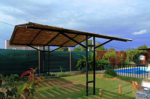 a roofed pergola in a garden with a pool at Cabañas Solares del Villicum in Albardón
