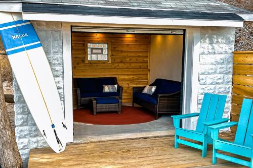 a screened in porch with two blue chairs and a surfboard at The Gatehouse on Orchard Beach in Lakeside