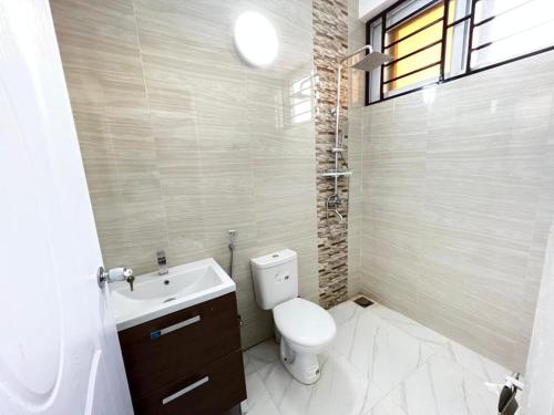 a bathroom with a toilet and a sink and a window at Remarkable 2-Bed Apartment Dar el Salam Tanzania in Dar es Salaam