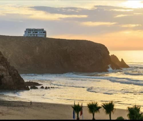 una playa con un edificio en lo alto de un acantilado en Dar diafa samira en Mirleft