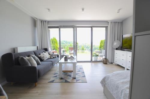 a living room with a couch and a tv at Apartament Na Bukowej - Wisła, widokowe studio in Wisła