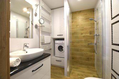 een badkamer met een wastafel en een wasmachine bij Apartament Na Bukowej - Wisła, widokowe studio in Wisła